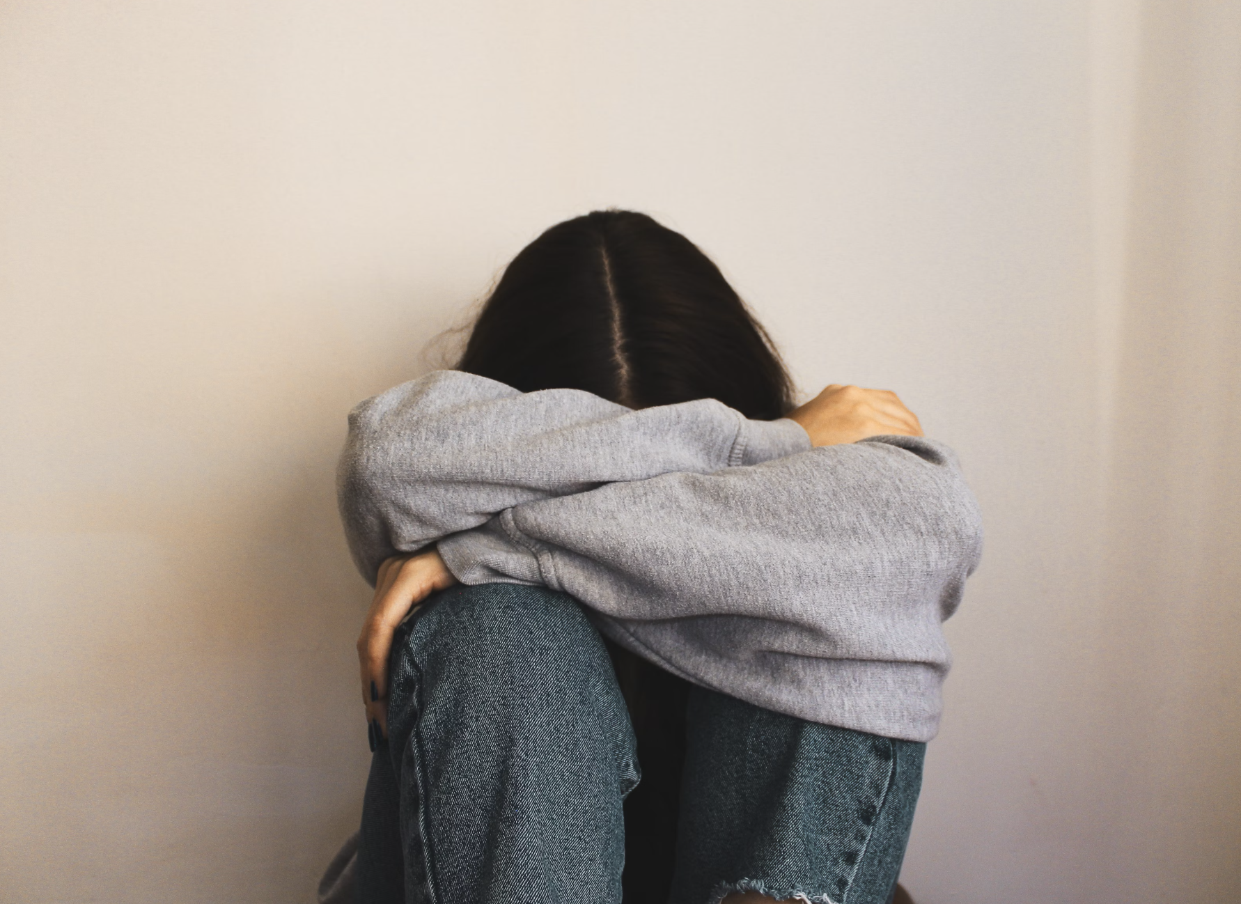 Woman sitting on the floor with arms wrapped around her head